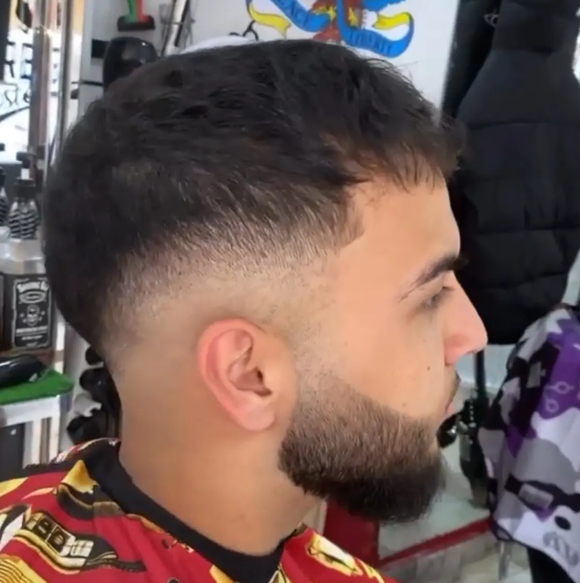 Sillón de barbería clásico con detalles dorados en Dennis Imperial Barber
